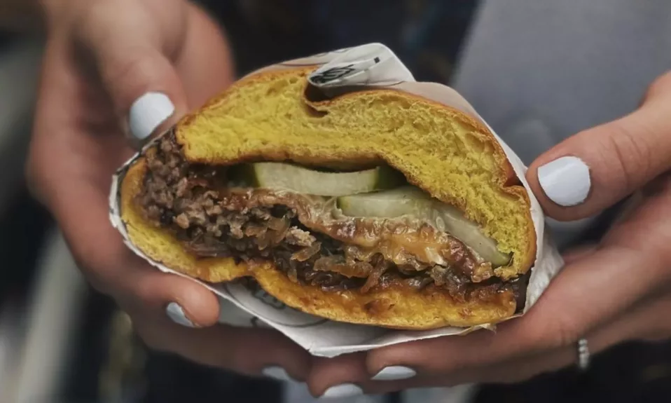 Burger tenu dans des mains manucurées.