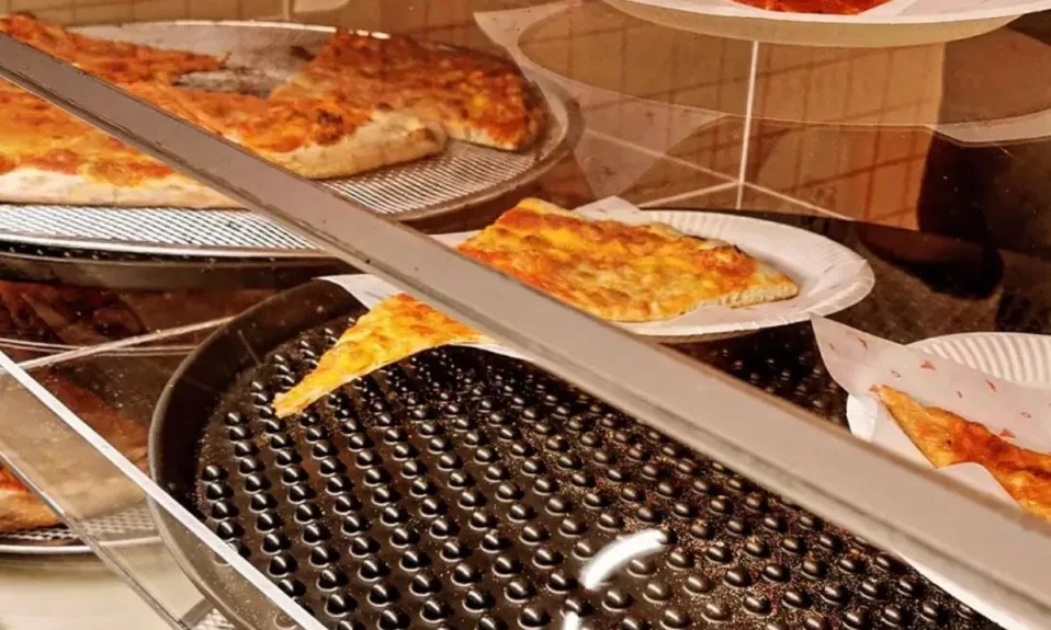 Vitrine de pizzeria avec tranches variées.