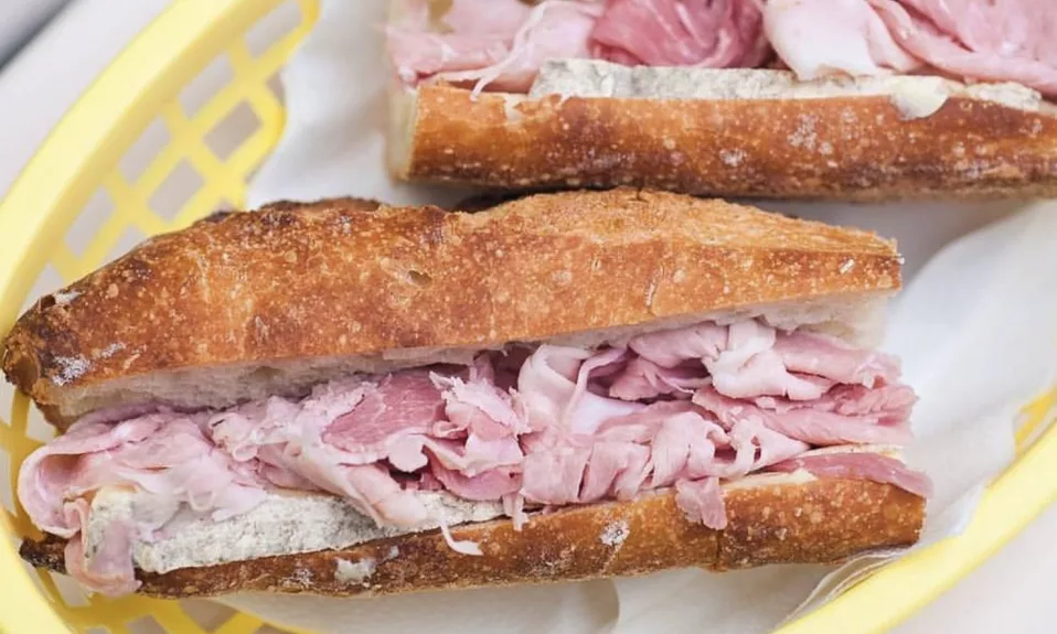 Baguette au jambon dans un panier jaune.