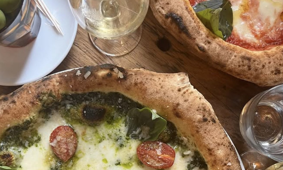 Deux pizzas avec verres de vin blanc.