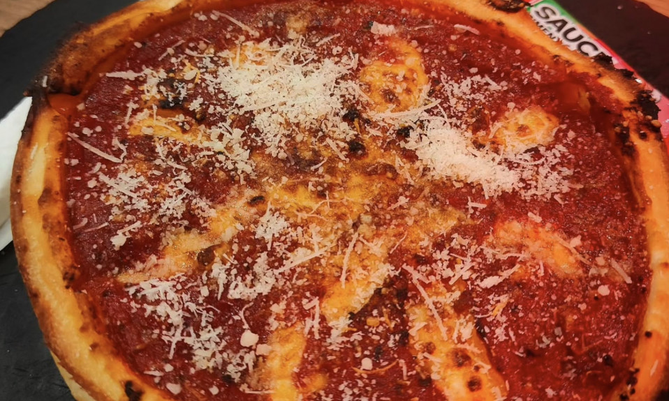 Pizza épaisse avec sauce tomate et fromage râpé.