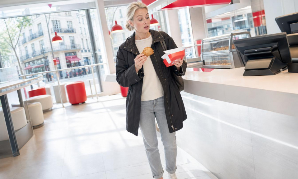 Femme surprise tenant poulet frit en fast-food