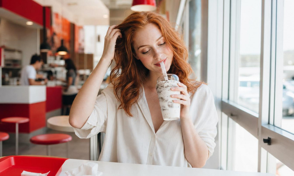 Jeune femme buvant un milkshake en restaurant